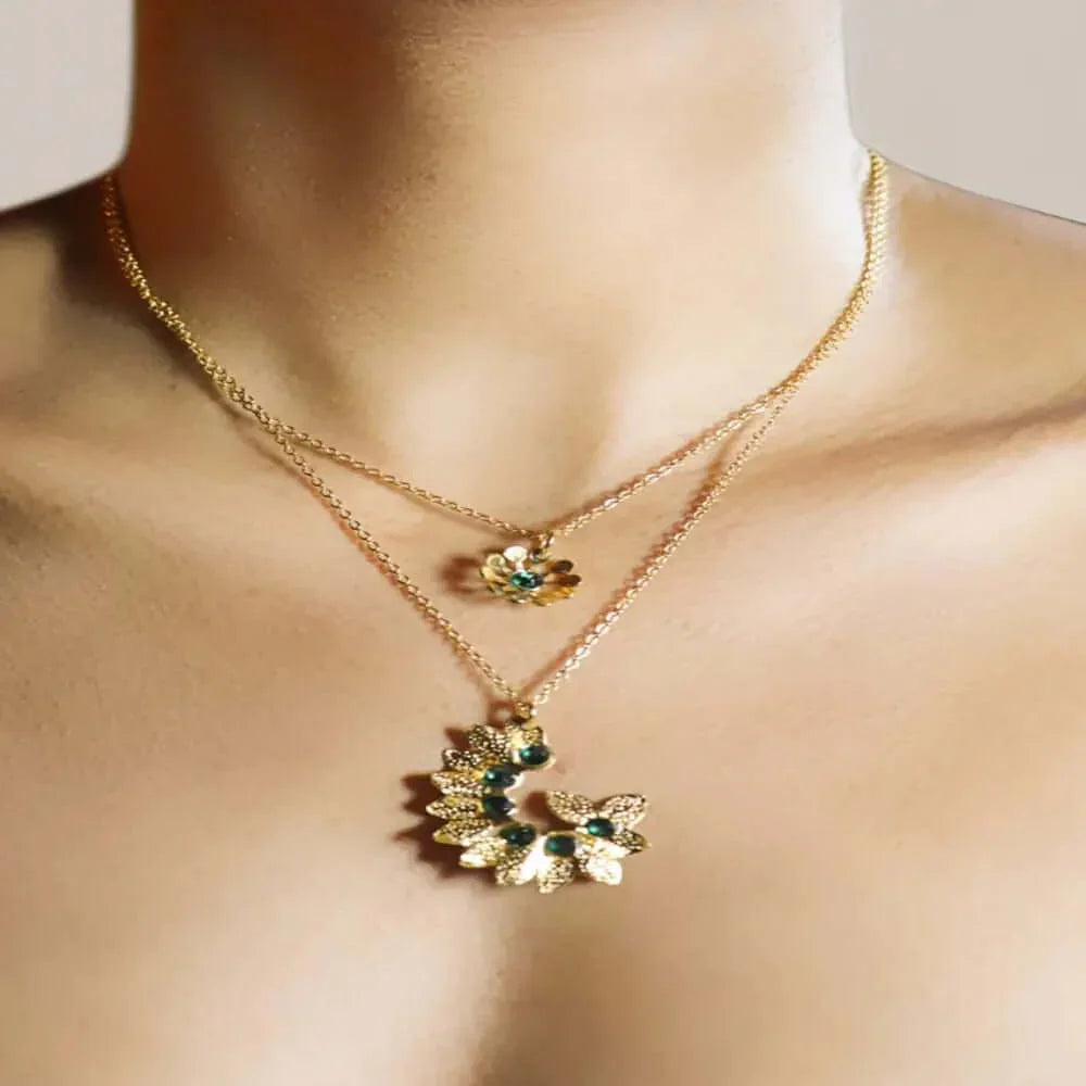 Layered gold necklaces with floral pendants featuring green gemstones on a woman's neck