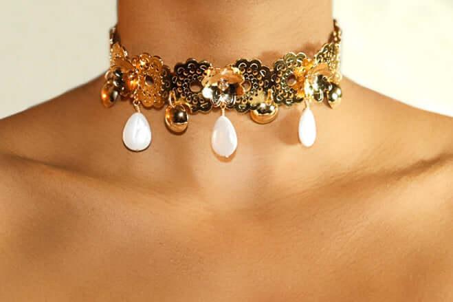 Gold floral choker with pearl drop pendants on woman's neck