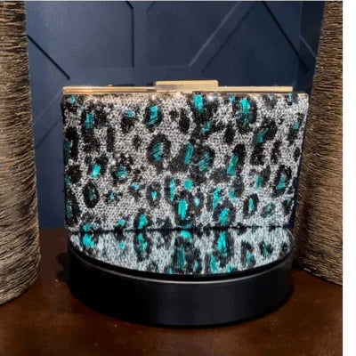 Leopard print clutch purse with teal accents on black reflective surface