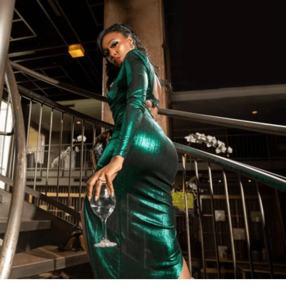 Woman in a shiny green dress holding a wine glass on a staircase in a modern venue